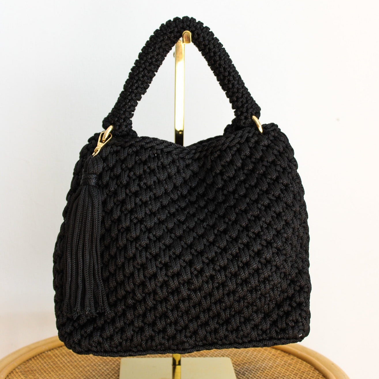Handmade black woven handbag. black crochet artisan made handbag with strap for shoulder or crossbody look. Gold detailing and fringe bag charm