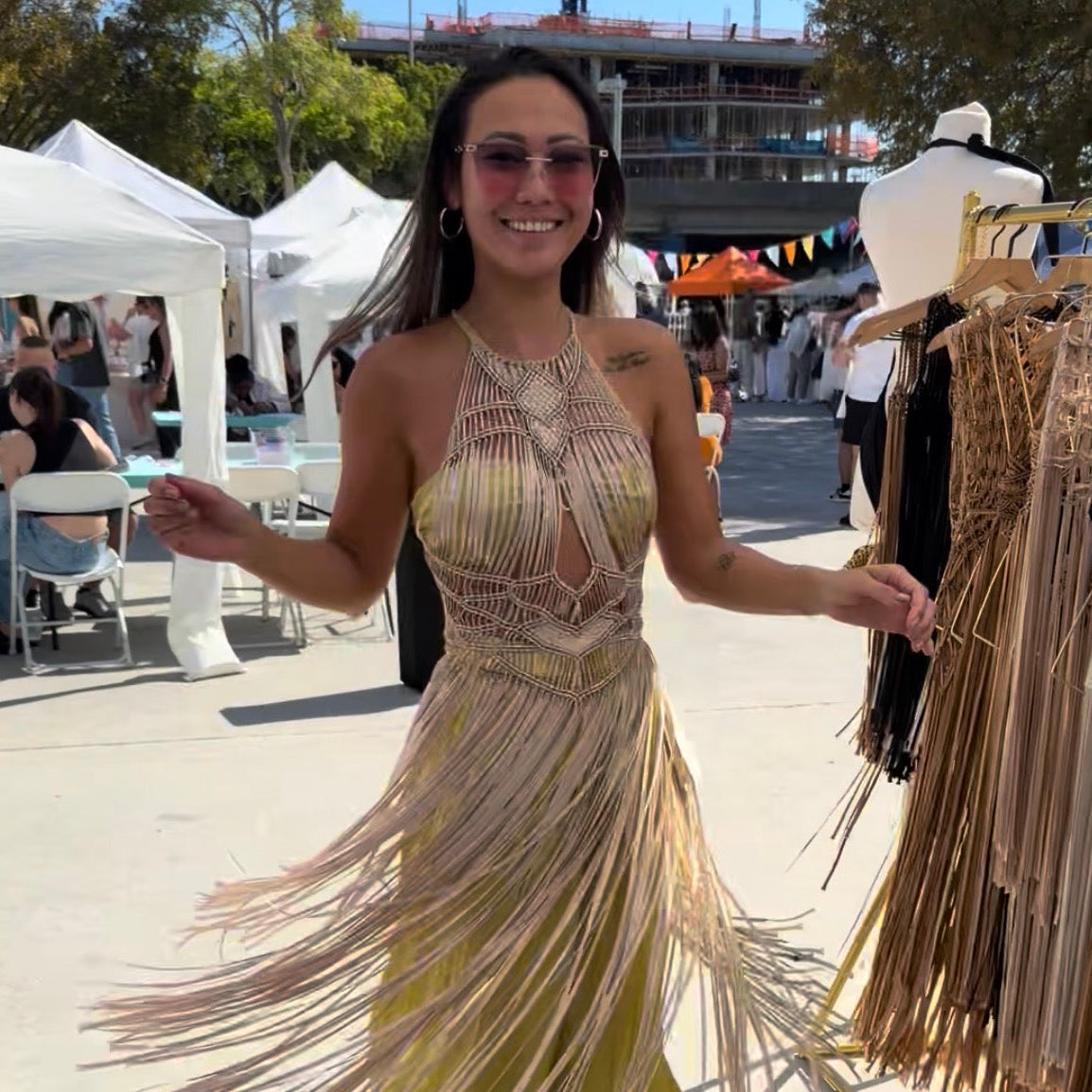 Woman wearing a fringe Luna Halter dress at an outdoor event and people in the background.