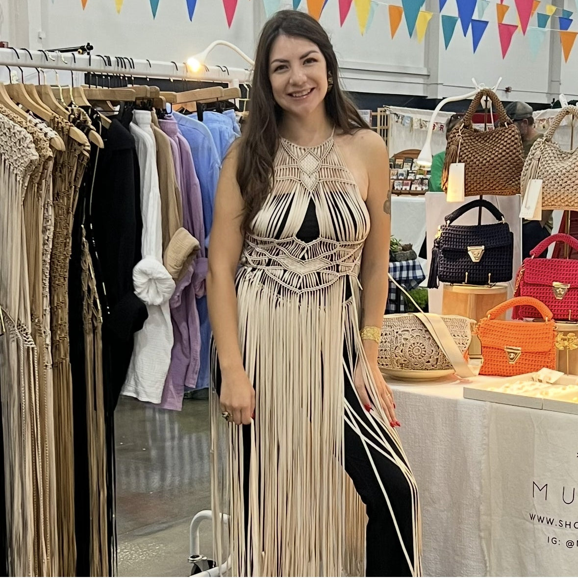 Woman in a dress standing in front of a display of handbags