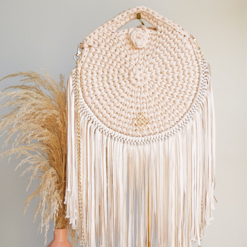 
                      
                        Rounded crossbody bag with fringes and chain strap. Crochet and macrame round bag. Boho Style. Color: Beige. Includes lining and zipper. 
                      
                    