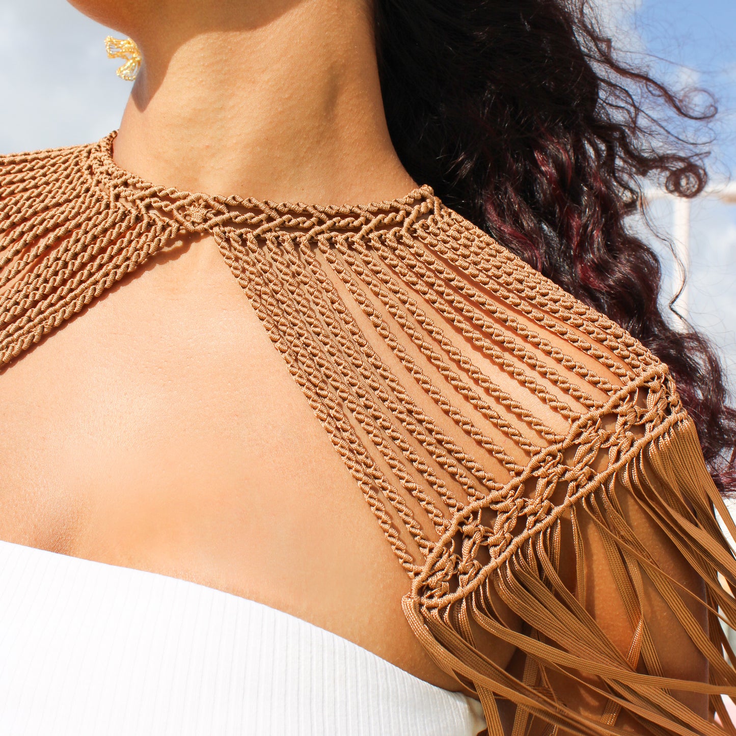 Caramel color macrame cape with intricate woven detail and flowy fringe