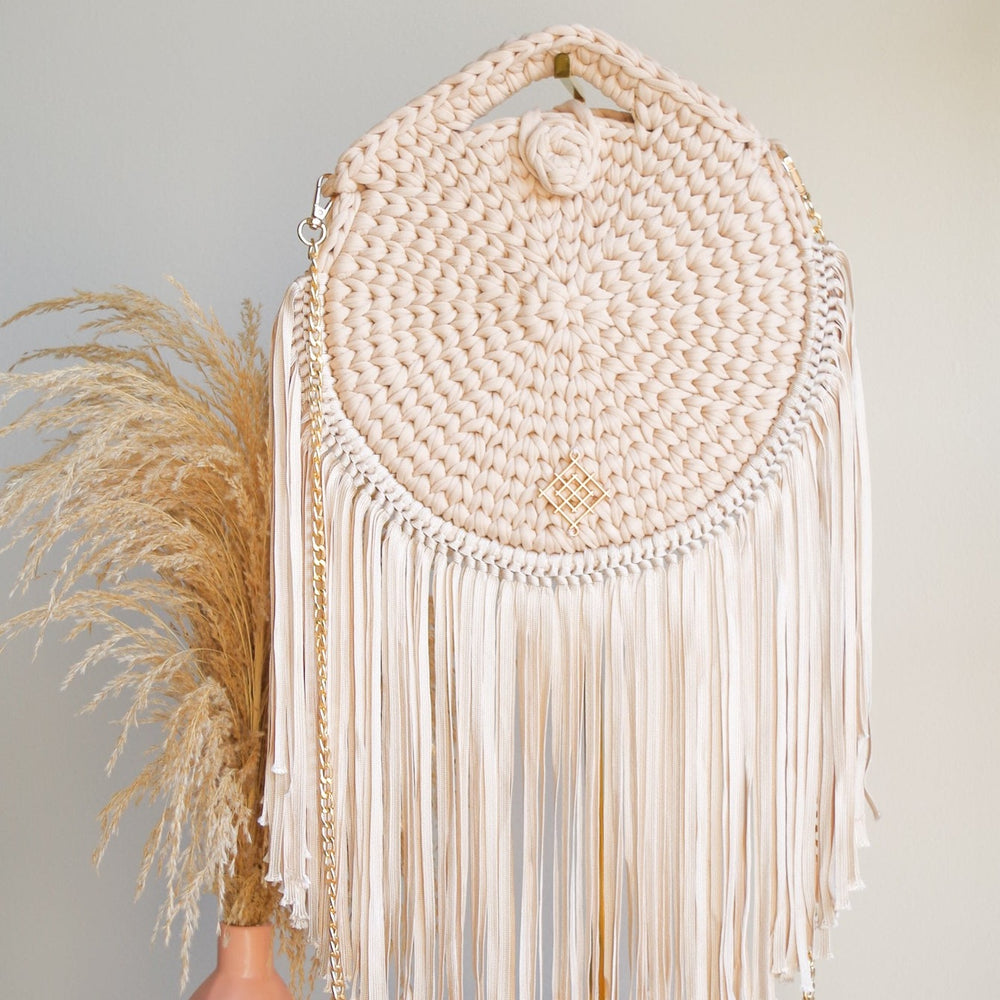 Rounded crossbody bag with fringes and chain strap. Made with crochet and macrame techniques. Boho Style. Color: Beige. Includes lining and zipper. Handmade in Bolivia. Hand Wash and professional cleaning only. 100% Rayon