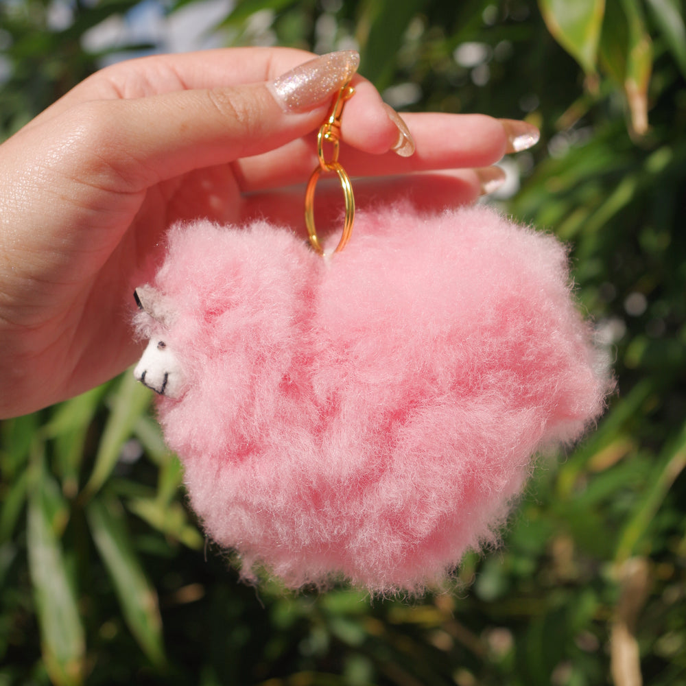 Pink side view Llama plushie pom pom keychain. Pom Pom size 3” in approx. Made with 100% alpaca wool. Made by Bolivian and Peruvian artisans. Colors Available: pink, white, beige, purple. Adult or children gift 