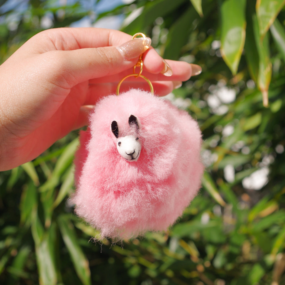 Pink Llama plushie pom pom keychain. Pom Pom size 3” in approx. Made with 100% alpaca wool. Made by Bolivian and Peruvian artisans. Colors Available: pink, white, beige, purple. Adult or children gift 