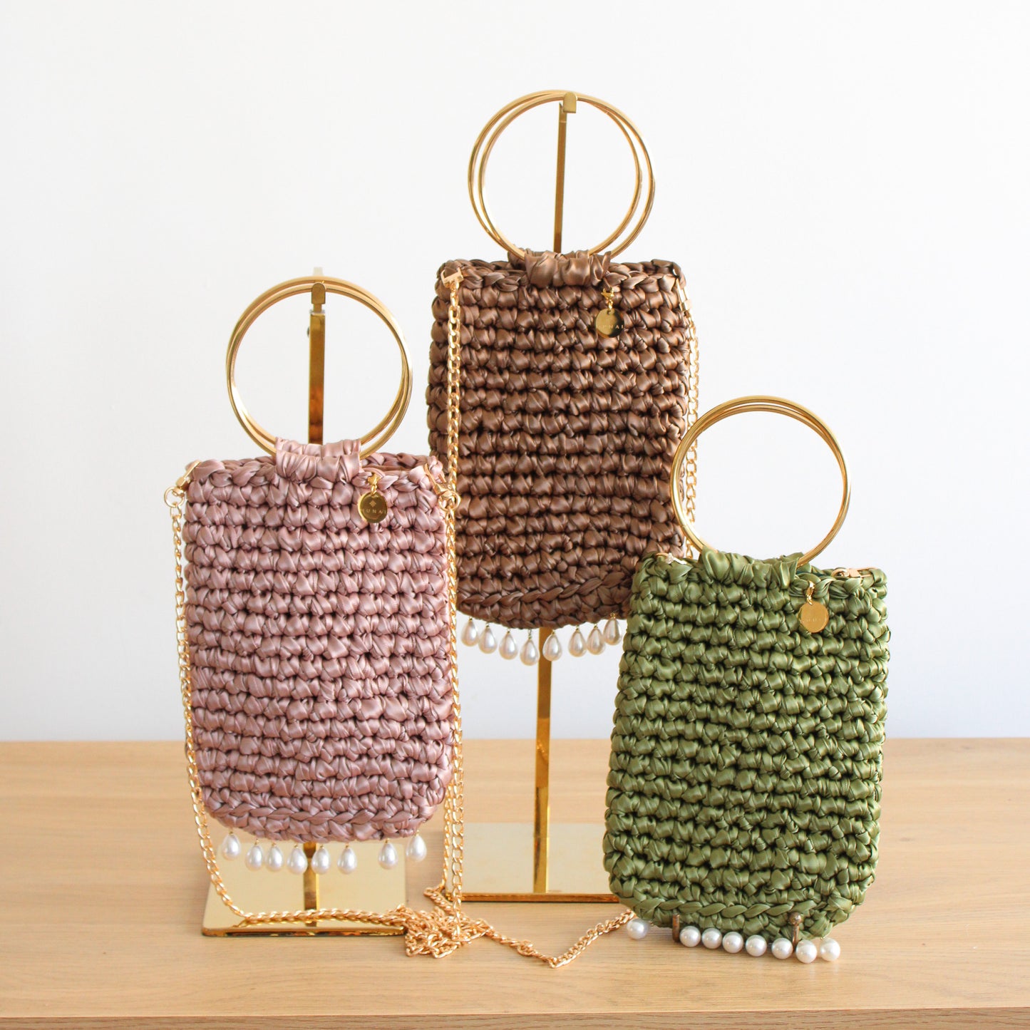 Three knitted handbags in different colors. Small handbags with pearls attached at the bottom