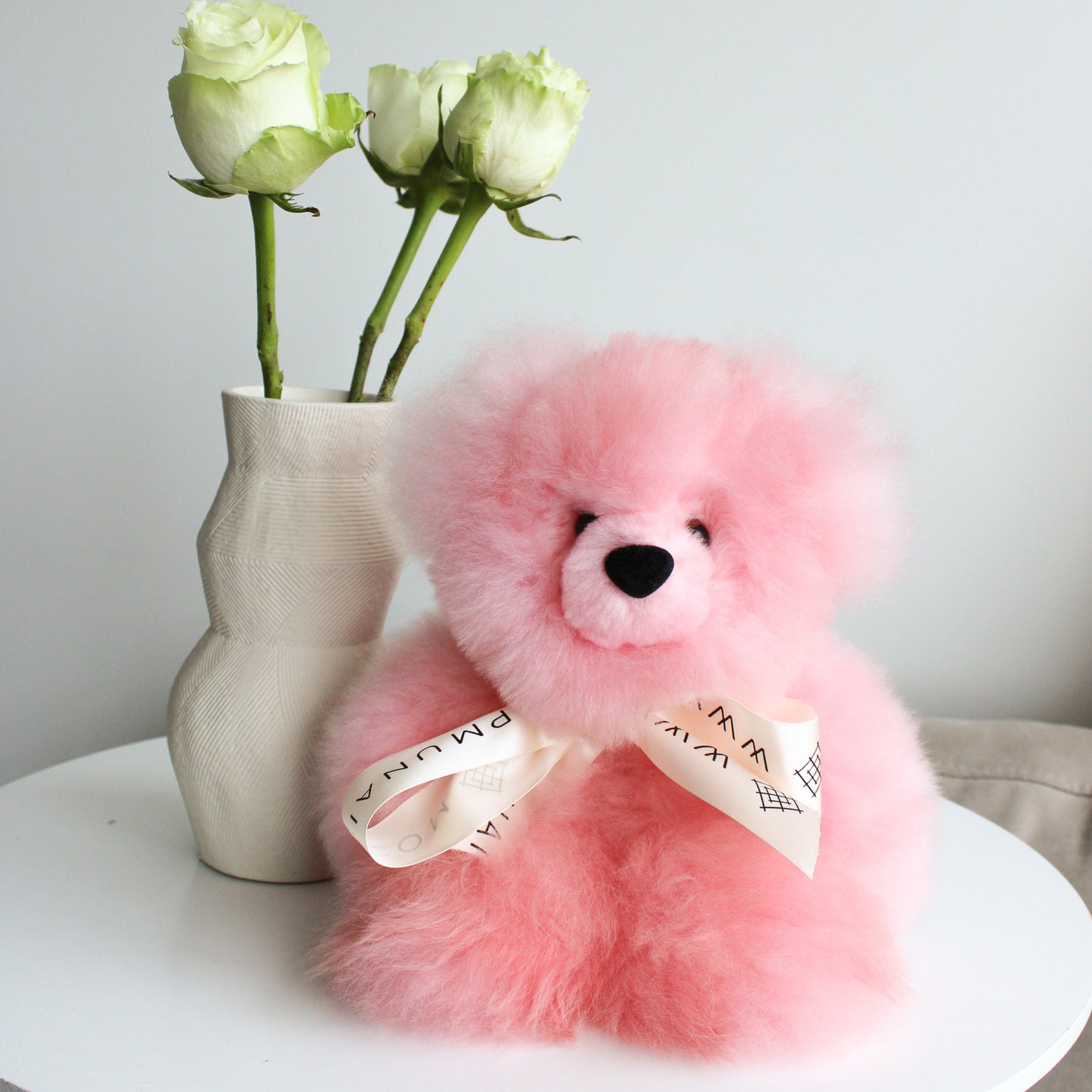Authentic alpaca fur fluffy teddy bear pink plushie with white bow. Light pink teddy bear
