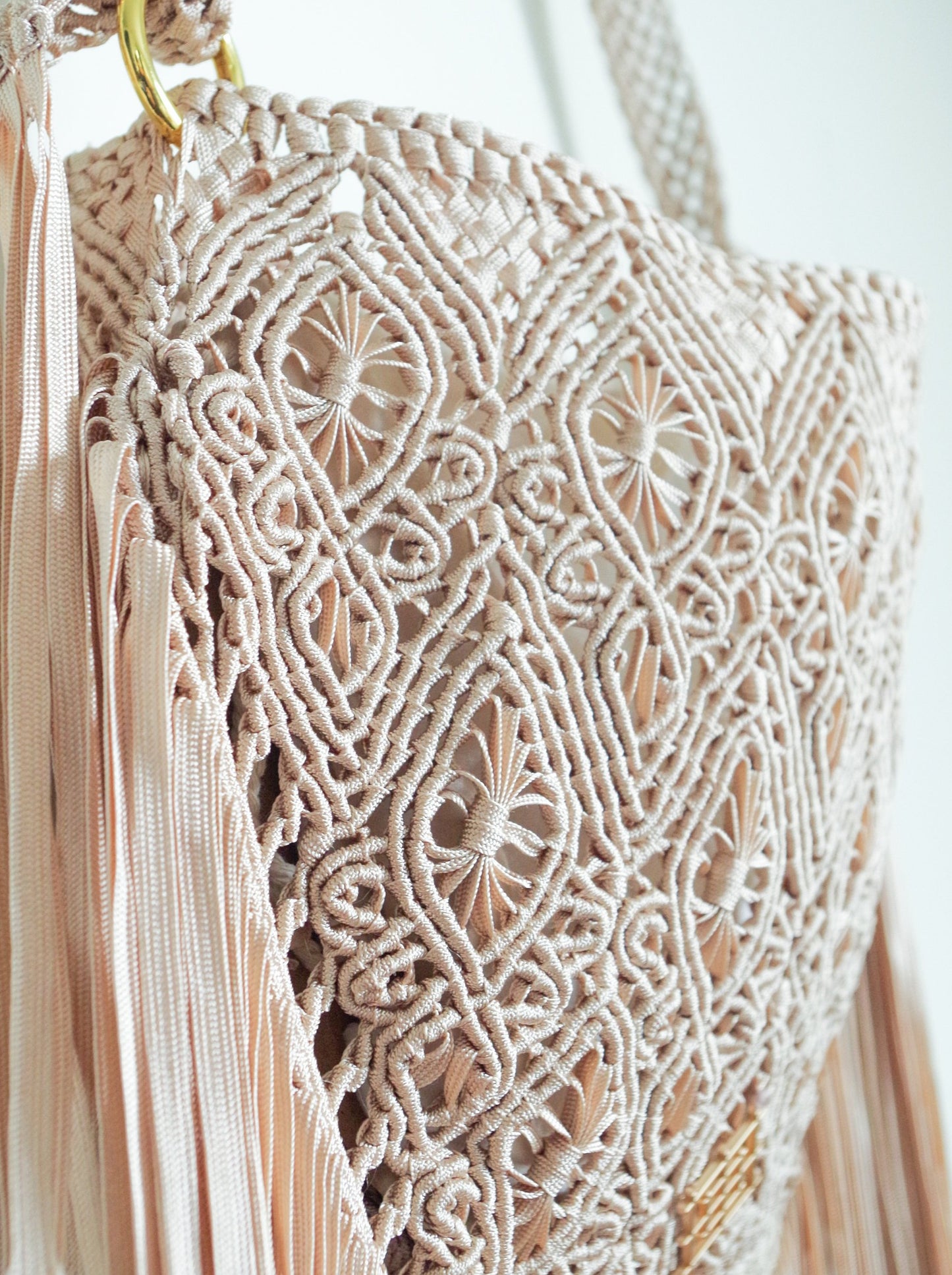 Beige Macrame crossbody bag with fringes. Includes lining and zipper. Handmade in Bolivia. Hand Wash and professional cleaning only. 100% Rayon