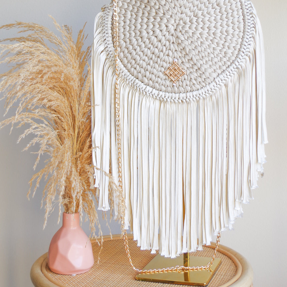 
                      
                        Rounded crossbody bag with fringes and chain strap. Made with crochet and macrame techniques. Boho Style. Color: Sand. Includes lining and zipper. Handmade in Bolivia. Hand Wash and professional cleaning only. 100% Rayon
                      
                    